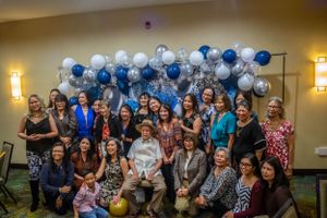 Wedding reception hall decorated with blue and white balloons and filled with celebrating guests.
