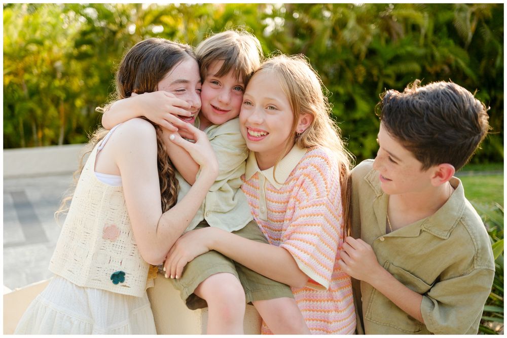 Children embracing and laughing together during a family photography session at St. Regis Punta Mita.