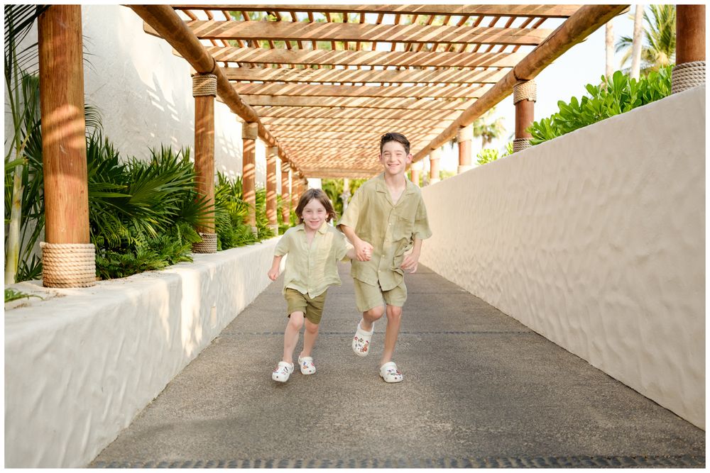 Two family members running through the walkways of St. Regis Punta Mita during a family photography session.