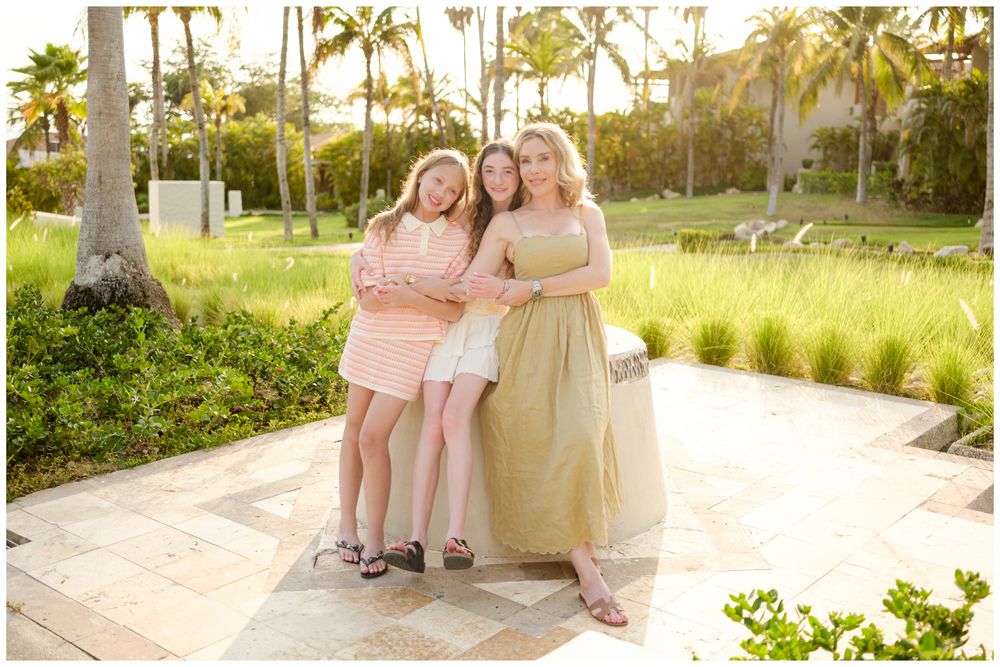 Family members posing on a sunny pathway with palm trees during a family photo session at St. Regis Punta Mita.