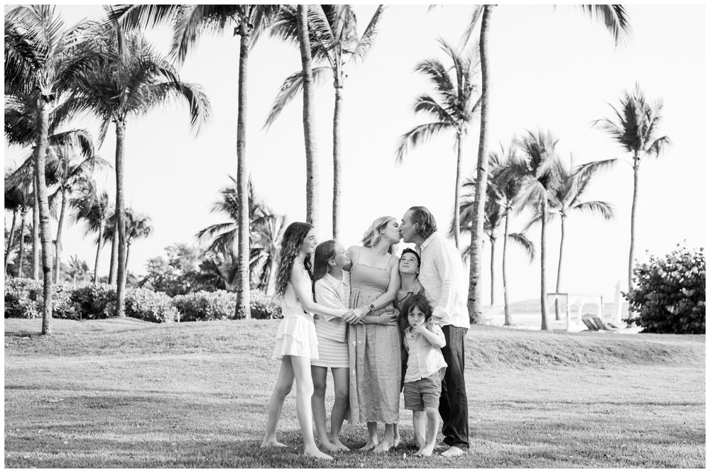 Black and white family portrait on a palm tree-lined lawn during a family photography session at St. Regis Punta Mita.