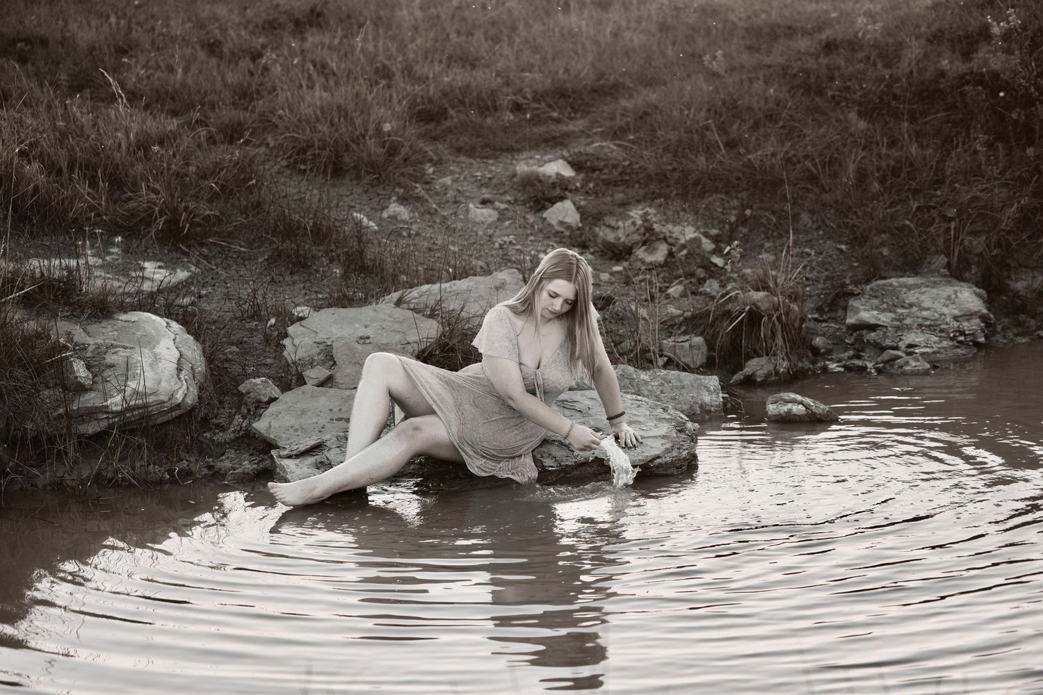 A series of black and white photographs showing someone lounging by a rocky stream in vintage-style dress.