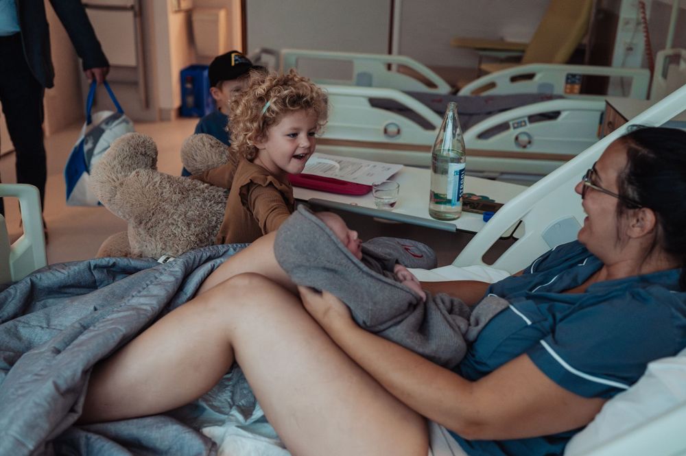 Hospital room scene with stuffed bear and medical equipment visible.