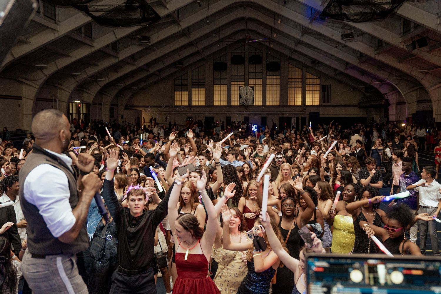 Energetic crowd fills indoor venue with raised hands during concert performance.