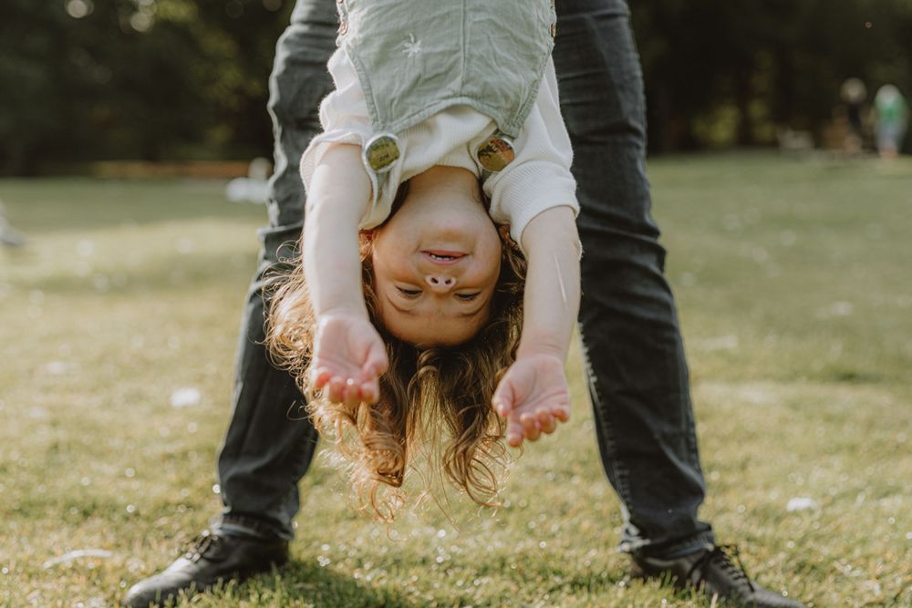 Playful upside-down moment captured in a grassy field during golden hour.