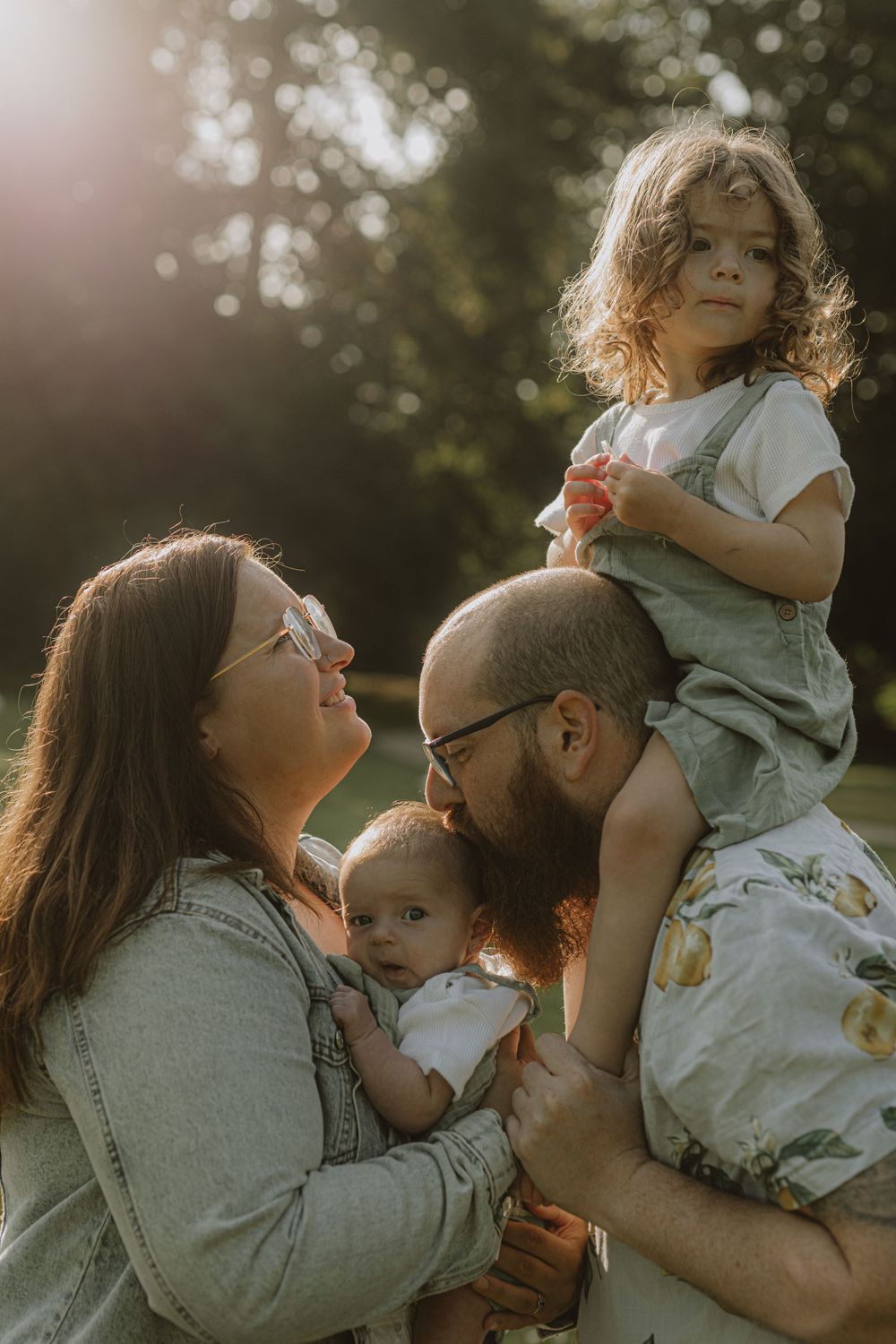 Intimate family portrait with warm backlighting in a natural outdoor setting.