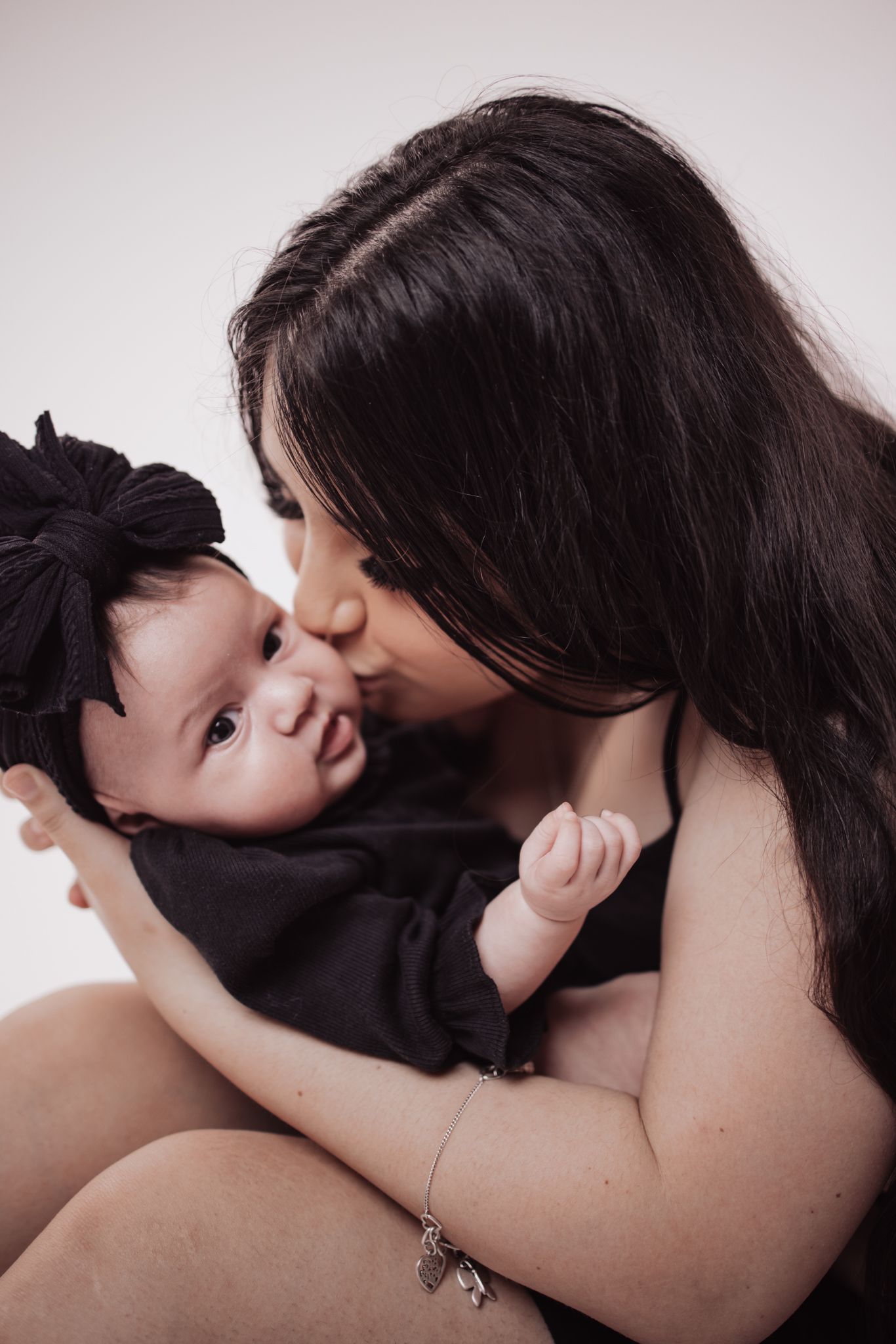 Tender moment between mother and baby in intimate black and white portrait.