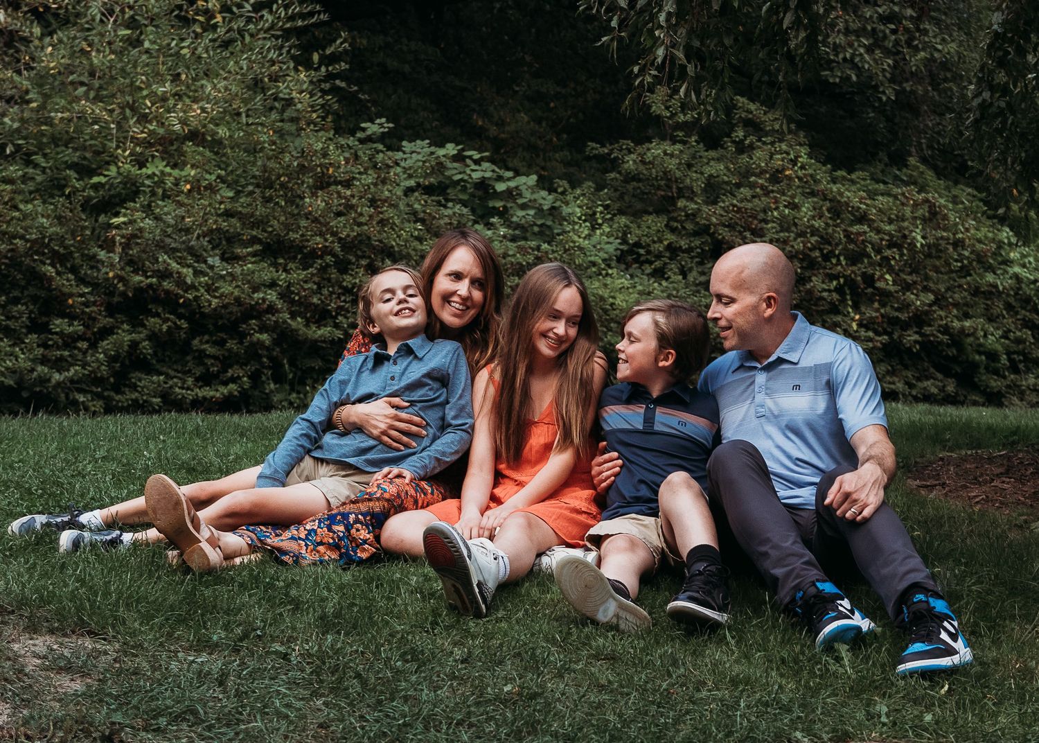 Family relaxing together on grass in a park during summer.