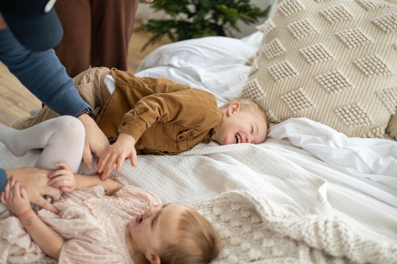 Two young children lying on white bedding during playtime.