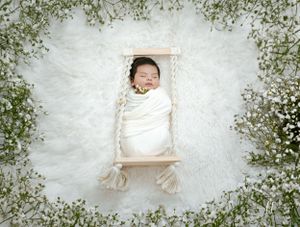 Baby lying on white backdrop surrounded by delicate baby's breath flowers.
