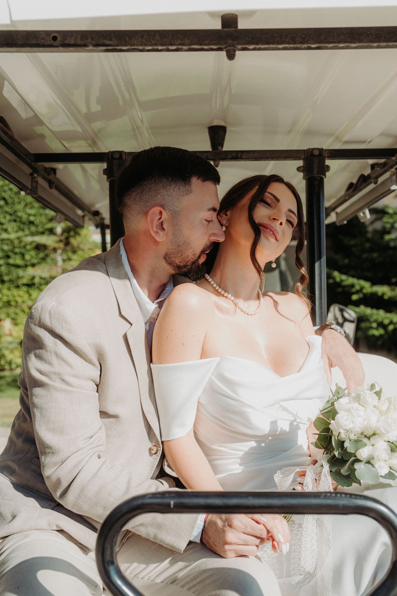 Romantic couple shares intimate moments in a golf cart during their wedding photoshoot.