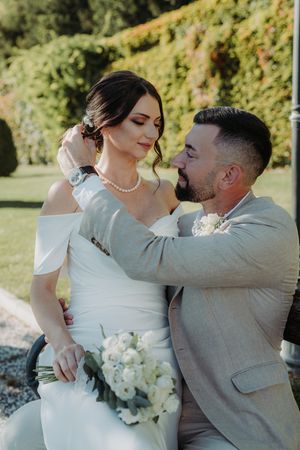 A romantic wedding photo series showing a couple embracing outdoors with white flowers against a green background.