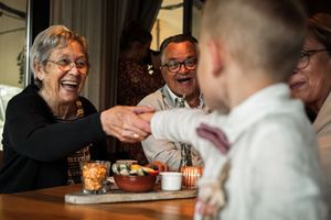 A group of people laughing and enjoying coffee together at a cafe table.