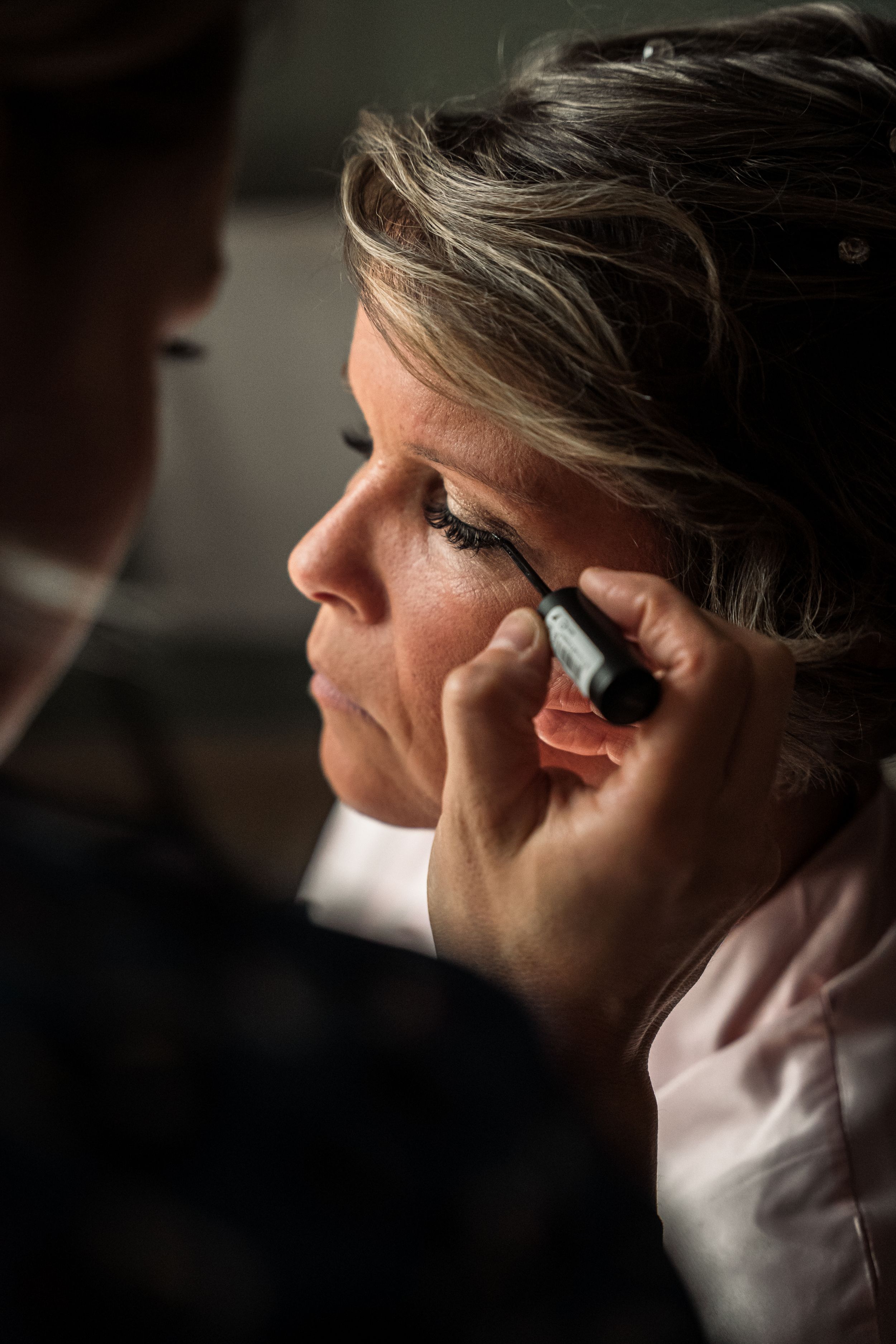 A series of dramatic profile portraits in dark lighting showing someone applying eye makeup in a step-by-step sequence.