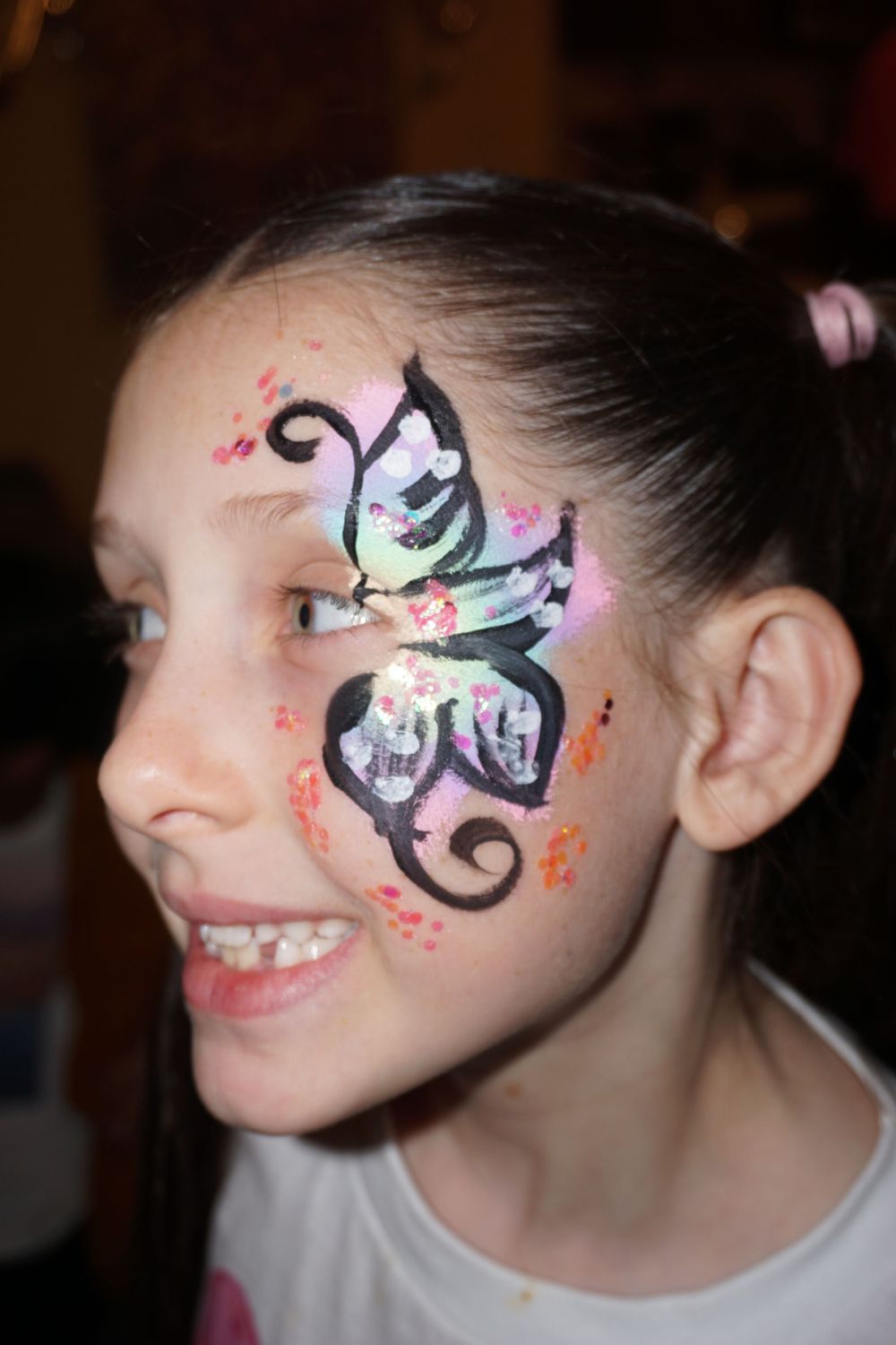 Decorative butterfly face paint design with sparkles and swirls.
