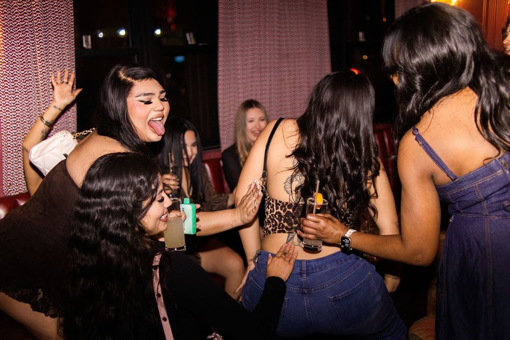 Group of women dancing and having fun at a nightclub party, holding drinks and enjoying the music.