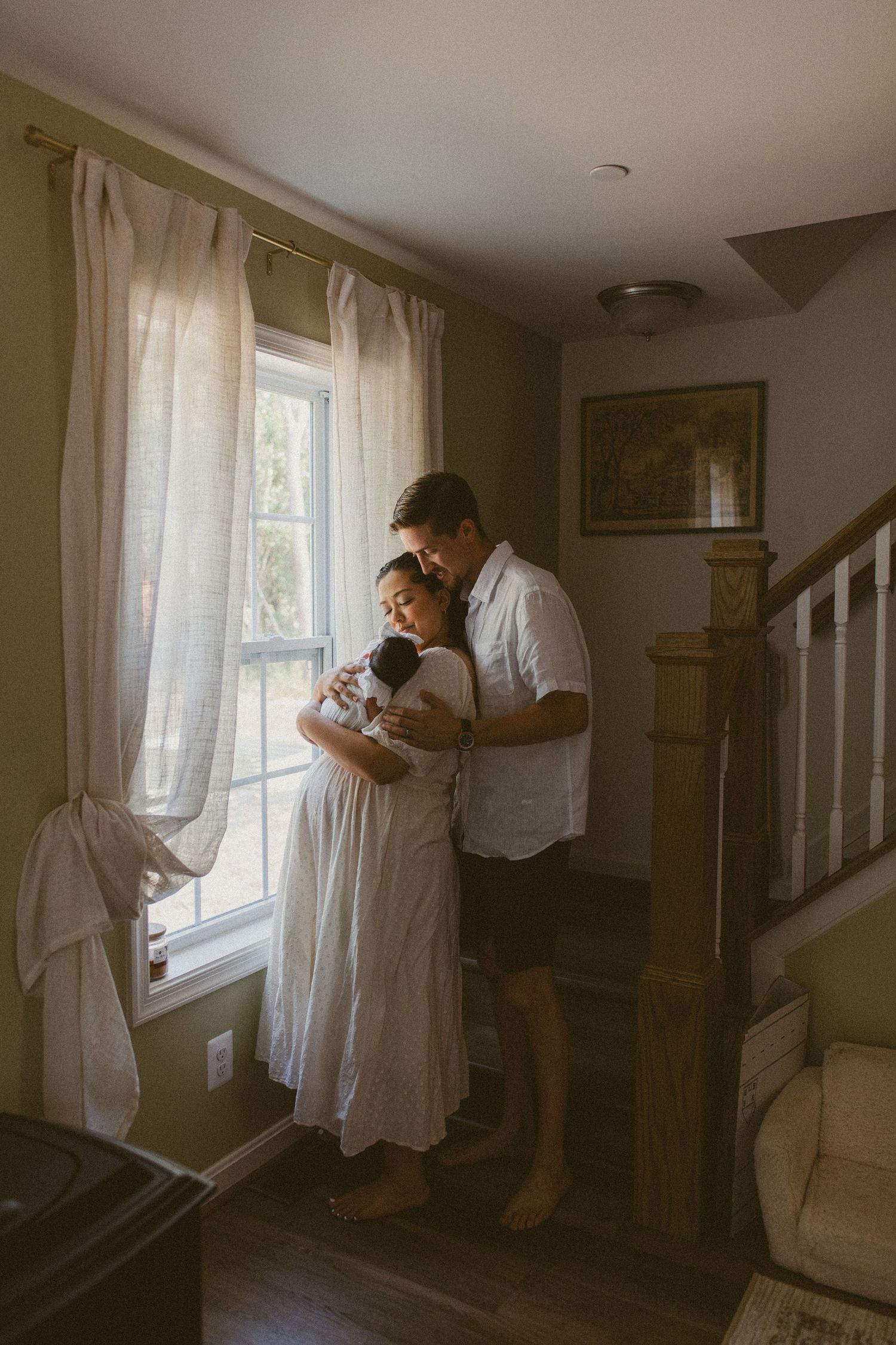 Intimate mother and newborn moment captured in soft indoor lighting.