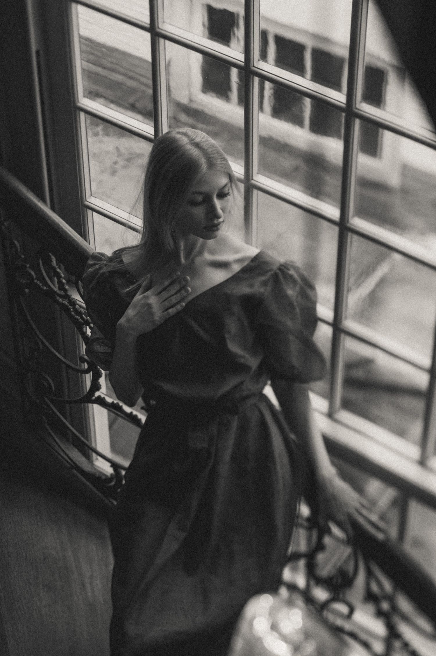 Artistic black and white photograph capturing movement near a window.