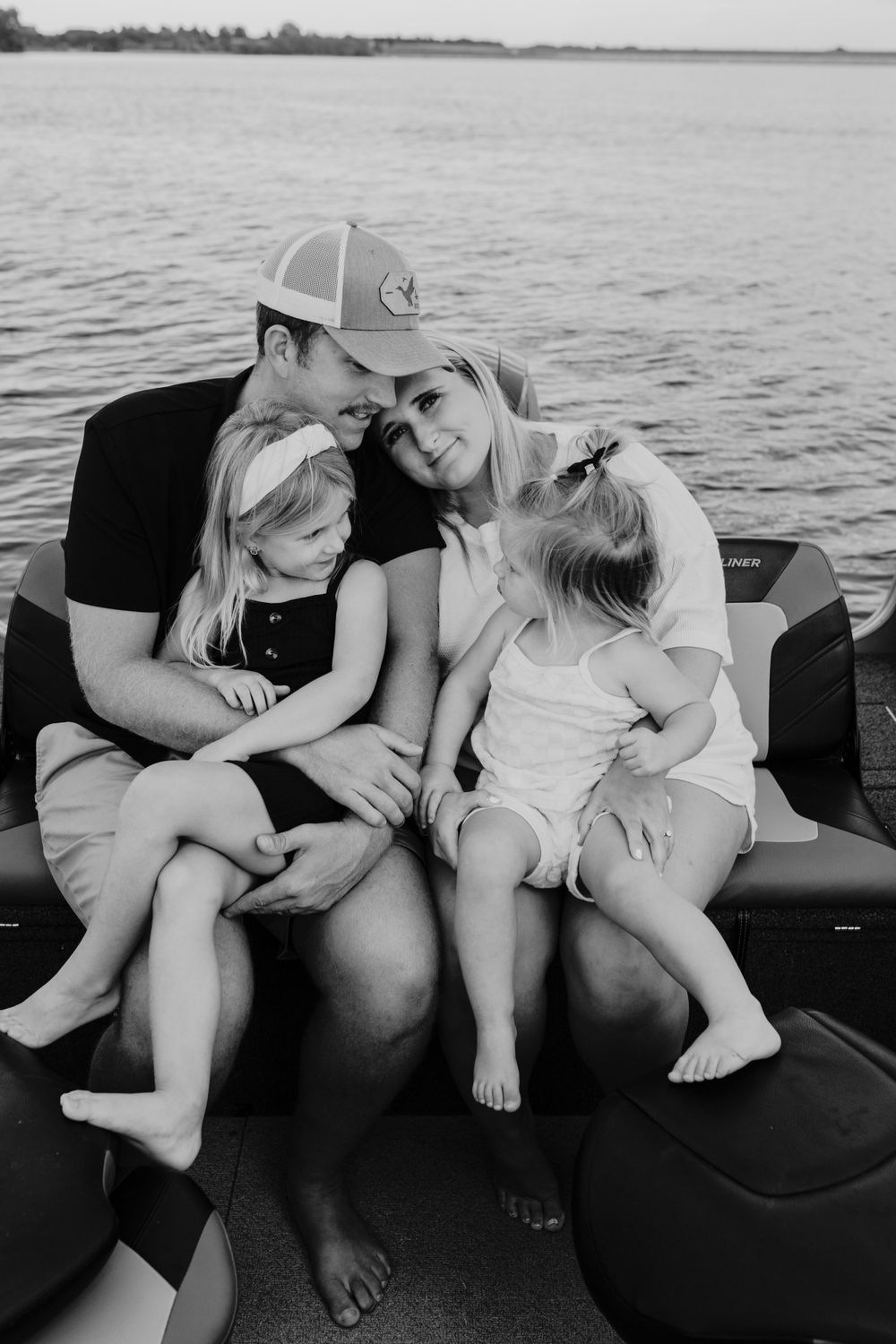 A sweet family moment captured in black and white on a boat on peaceful waters.