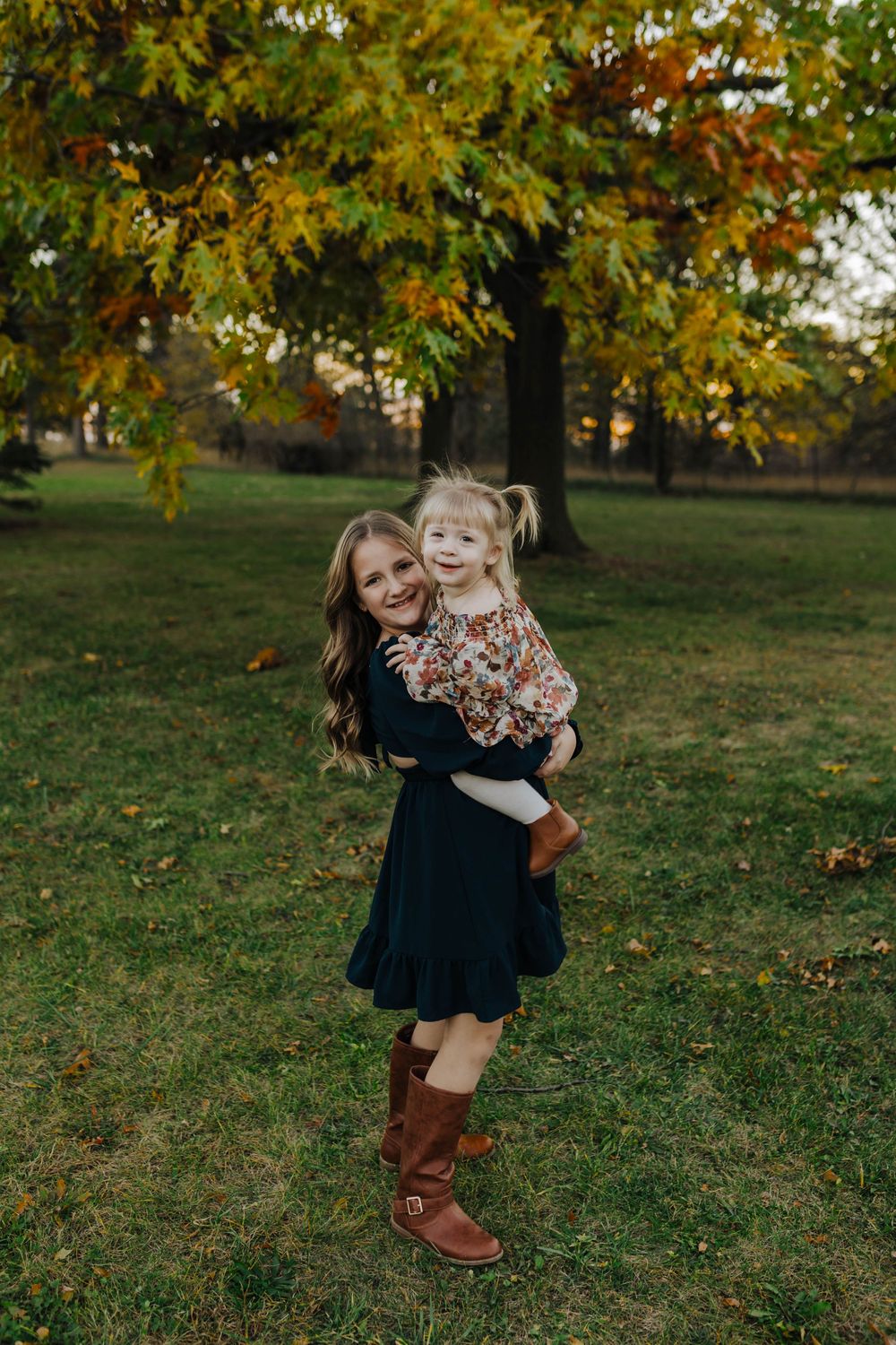 A pair in coordinated outfits share joyful moments together on an autumn day with golden leaves in the background.