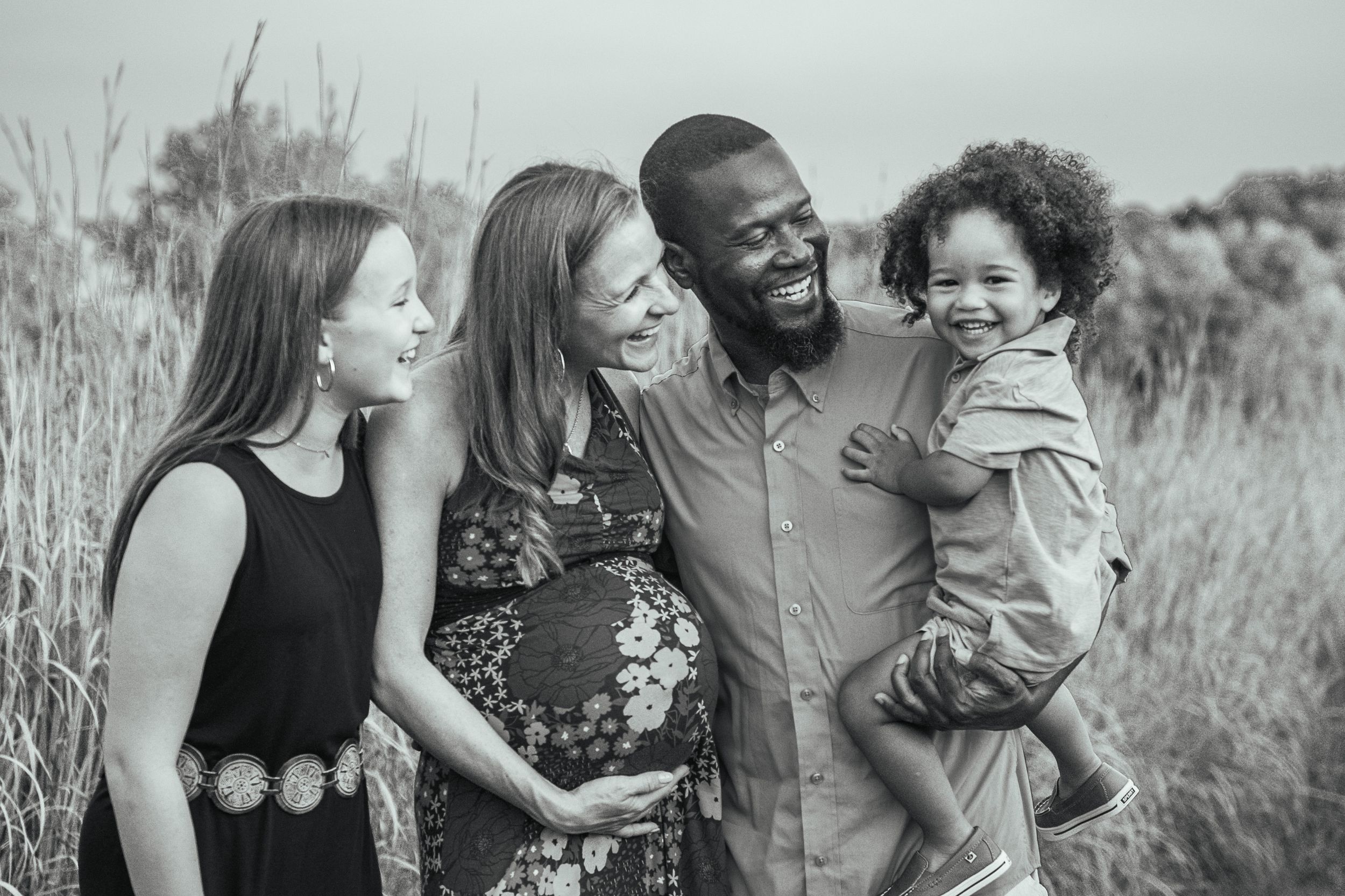 A joyful family shares laughter together in a field of tall grass.