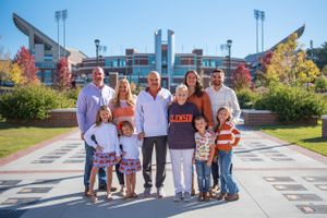 A group poses together outside a large sports stadium on a sunny day.
