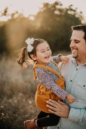 A joyful moment between two people sharing laughter during golden hour in an outdoor setting.