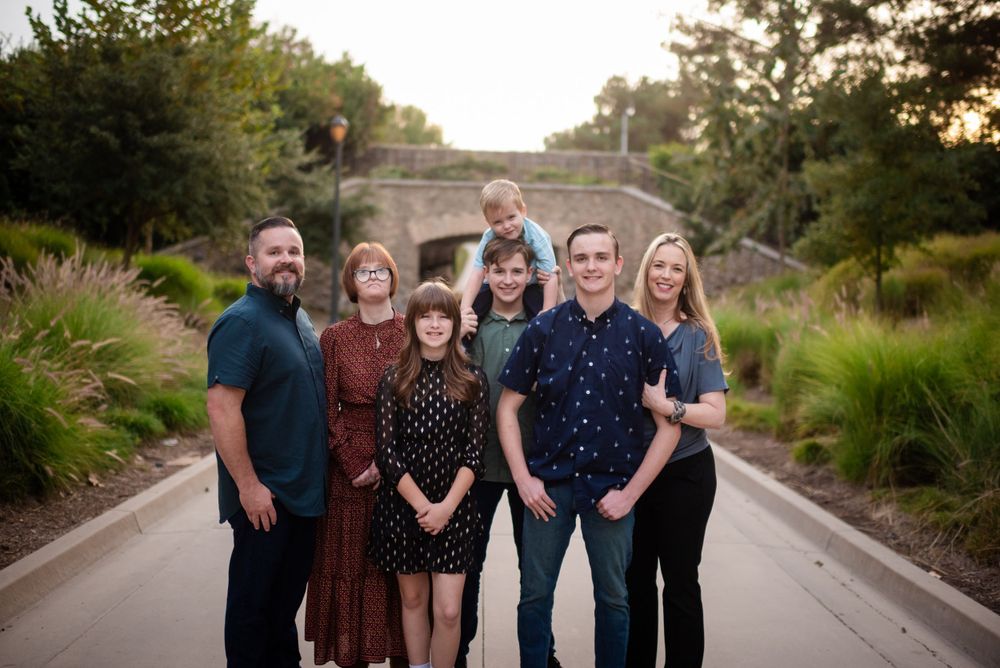 Group portrait of family members standing together on a paved pathway at dusk.