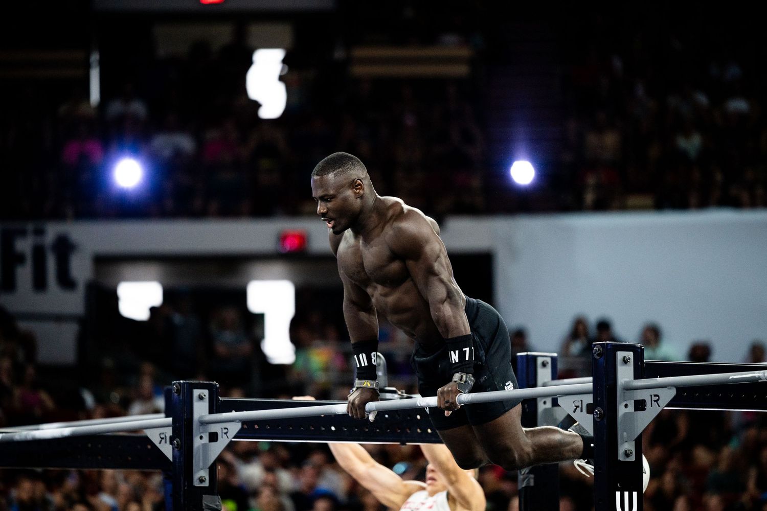 Athletic performer executing impressive gymnastic move on parallel bars during competition.