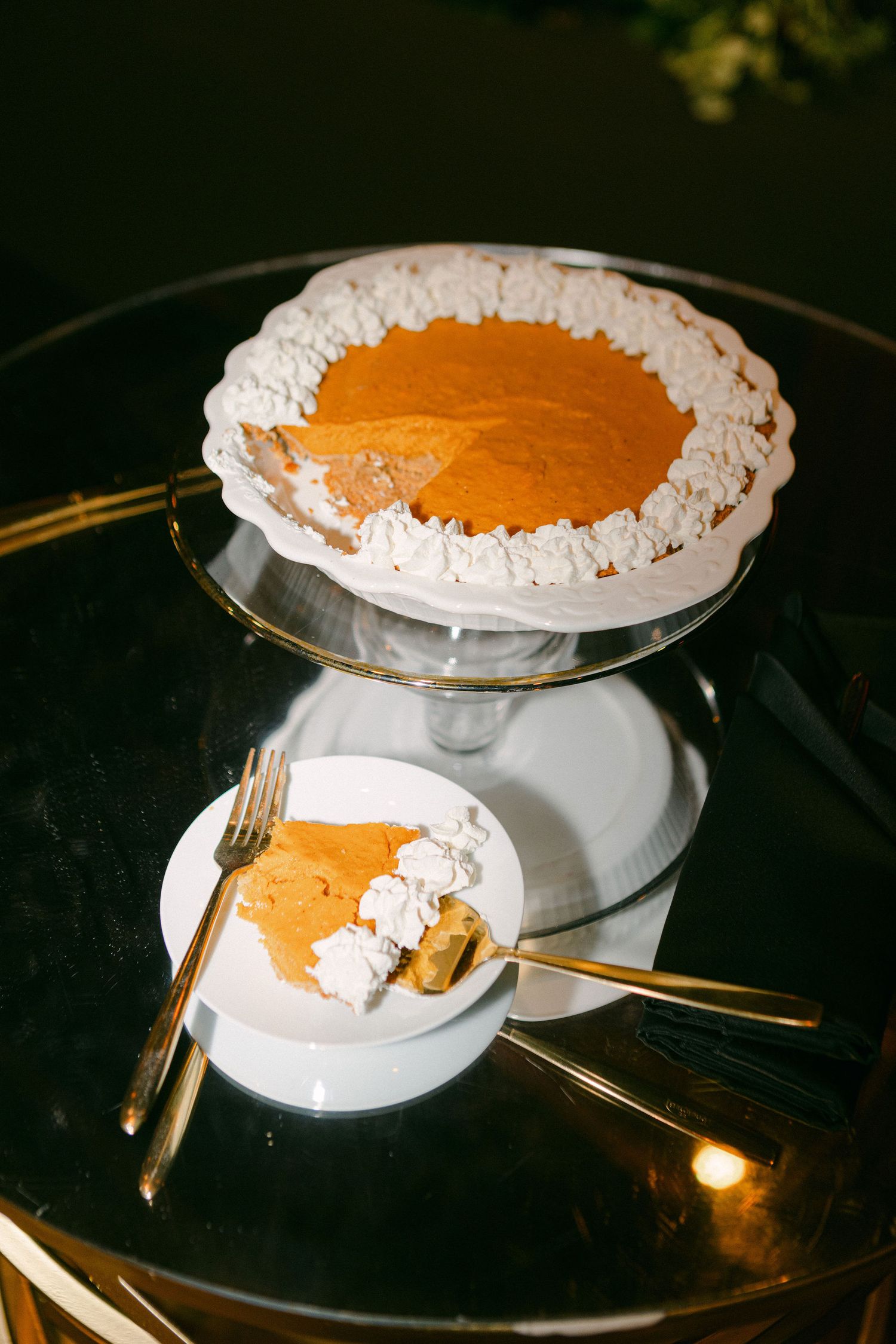 An elegant pumpkin pie with whipped cream border on a gold-rimmed cake stand.
