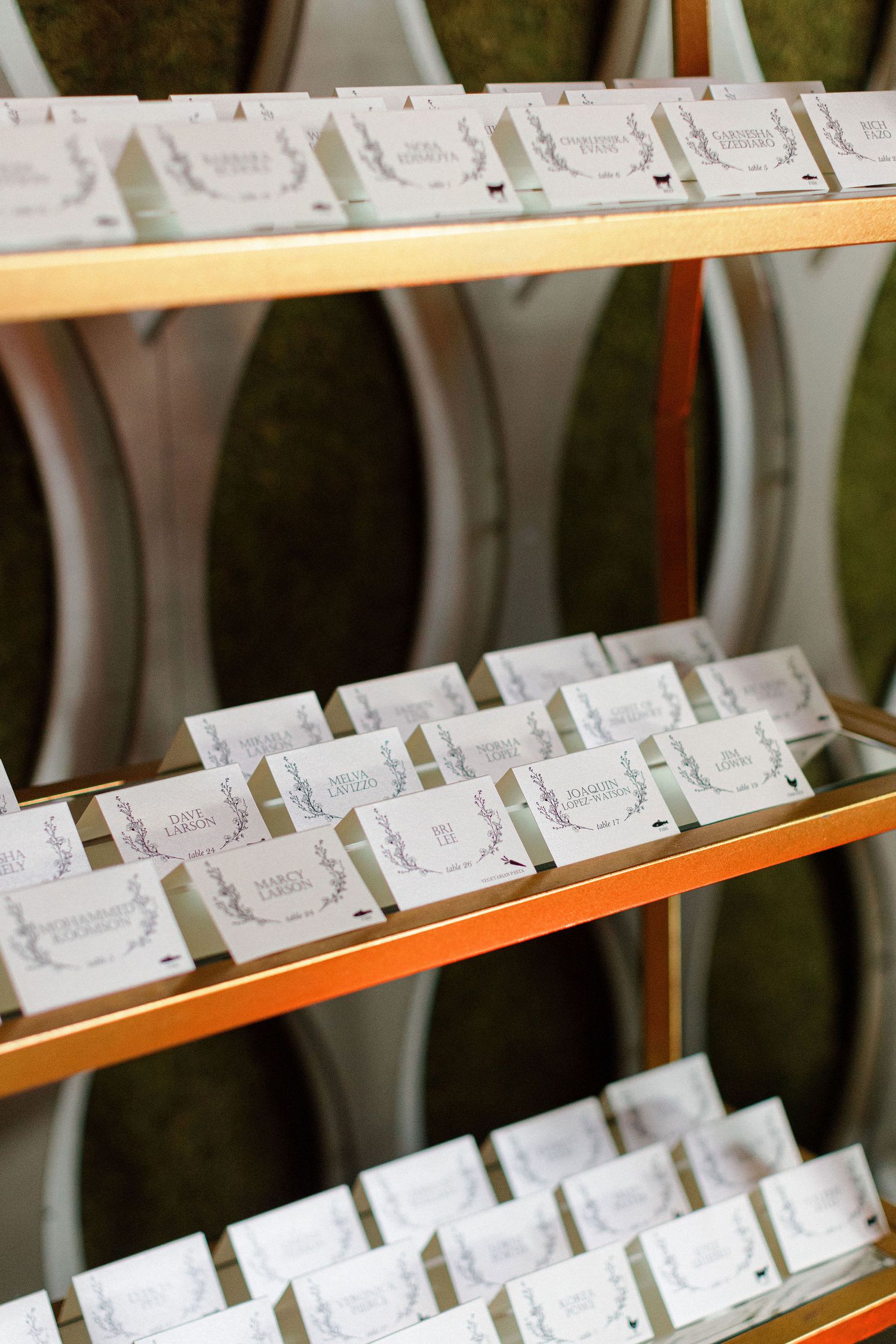 Rows of elegant white place cards displayed on wooden shelves.