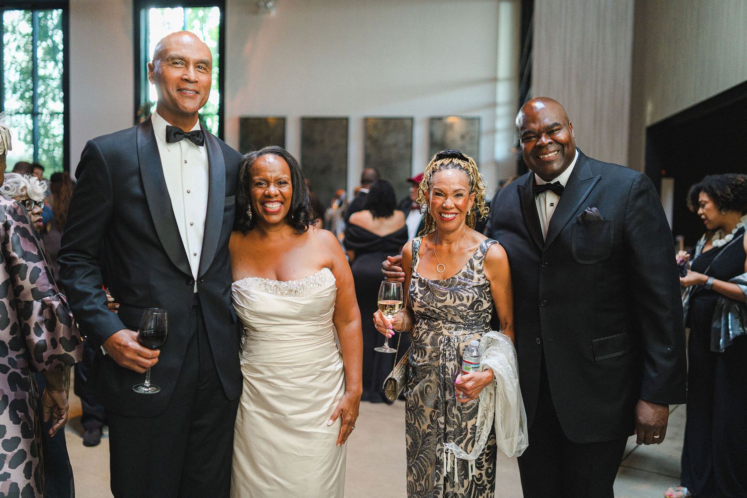 Formal wedding guests in evening attire posing at an elegant reception.