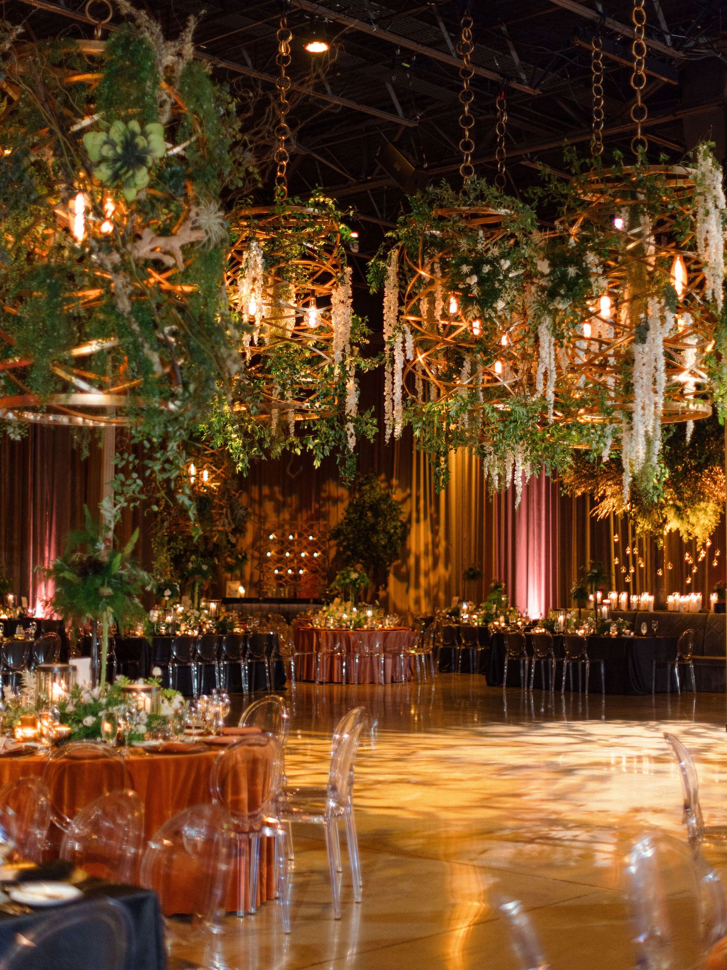 Luxurious reception hall decorated with hanging greenery and warm lighting.