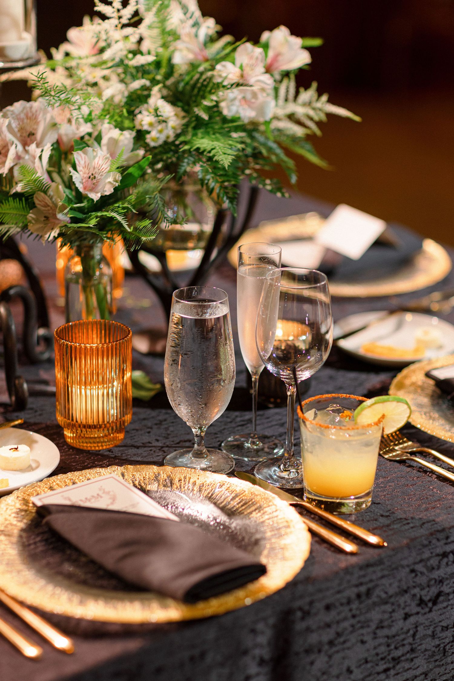 Elegant table setting with pink floral centerpiece and gold-rimmed charger plates.