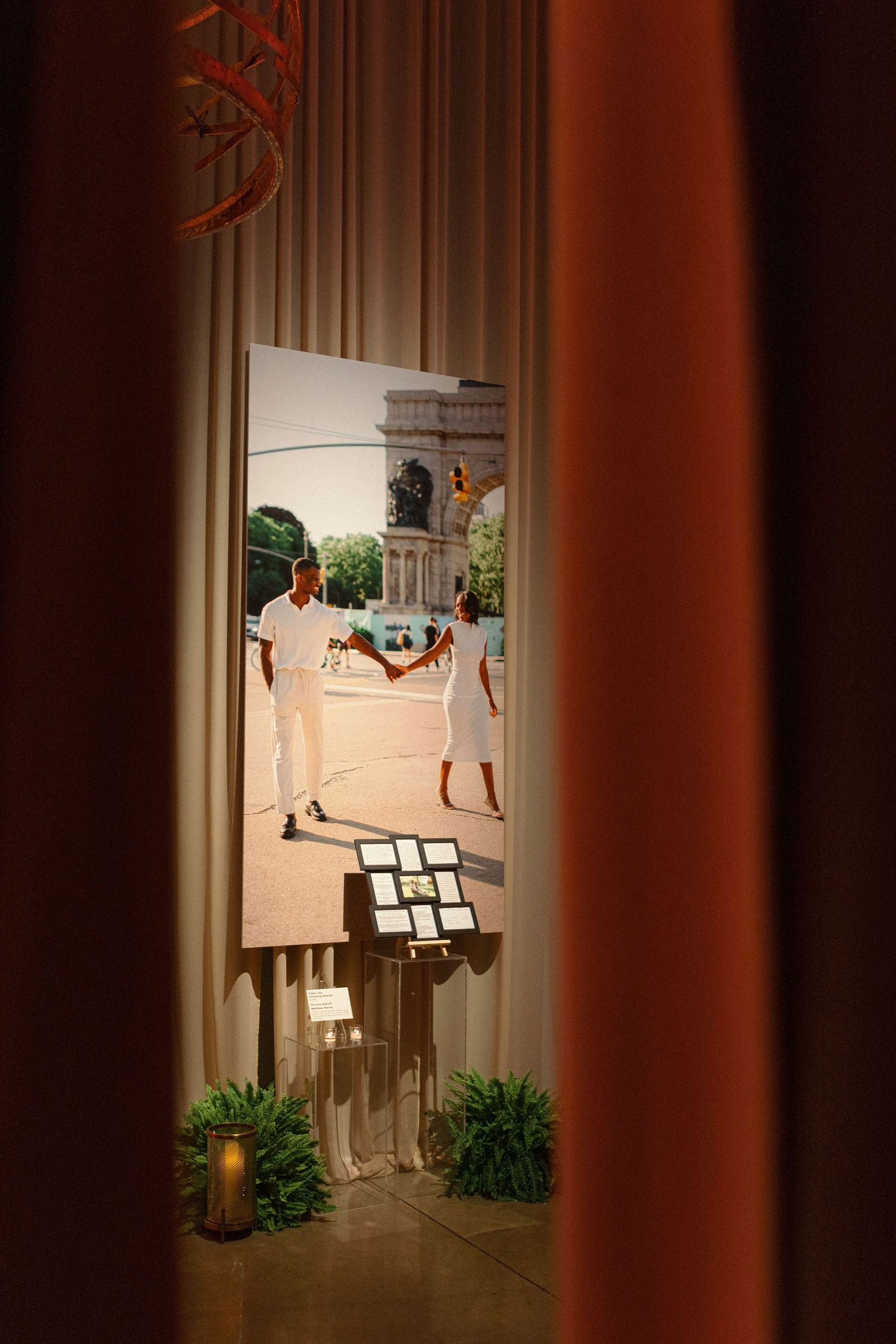 A glimpse through curtains of a formal event setup with a music stand and potted plants in the foreground.