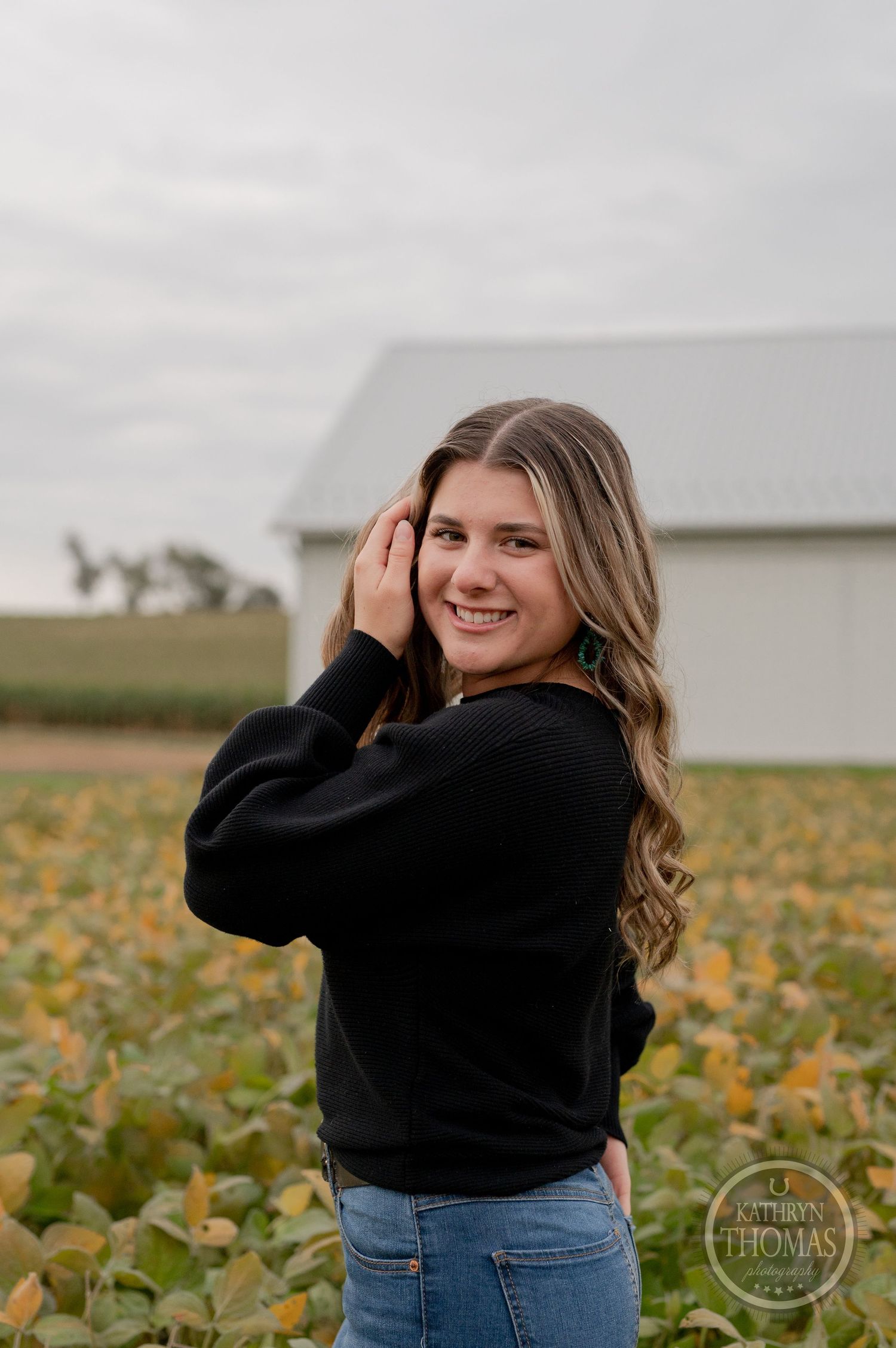 Outdoor portrait in front of a white barn with autumn pumpkin field scenery.