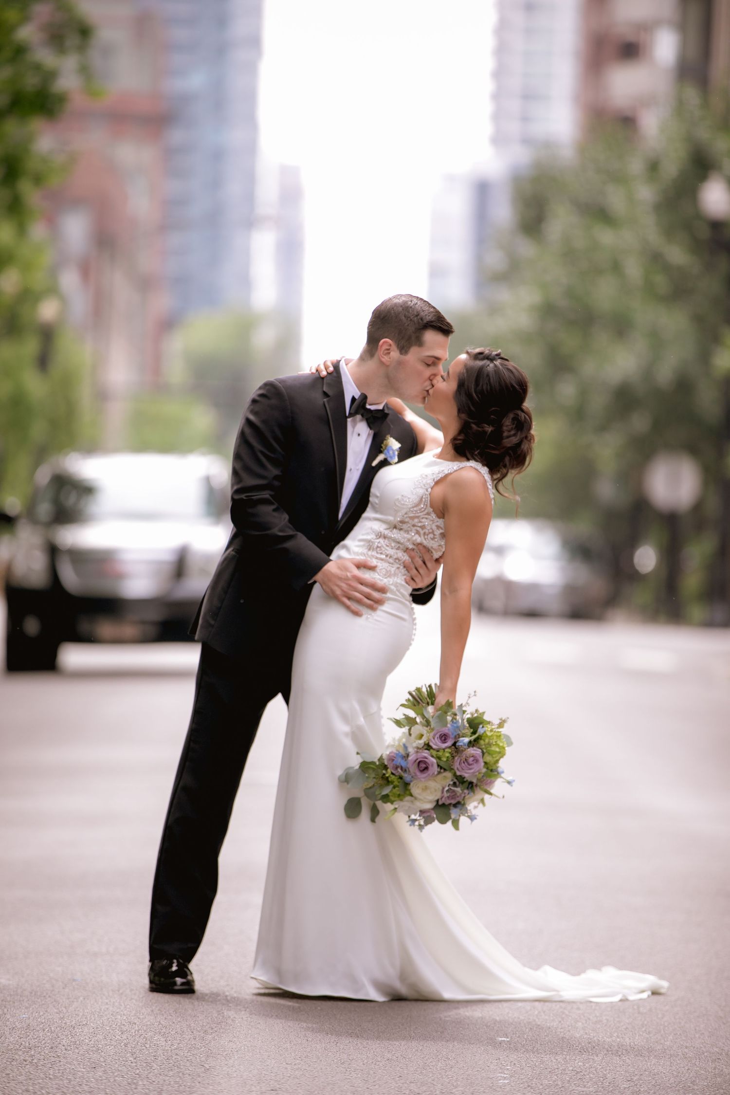 A romantic street wedding photo with city buildings in the background.