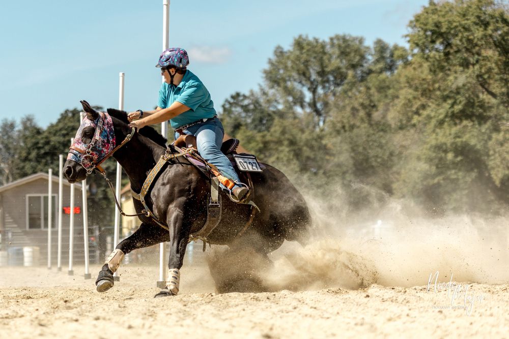 Horse and rider kick up dust while making a sharp turn during barrel racing competition.