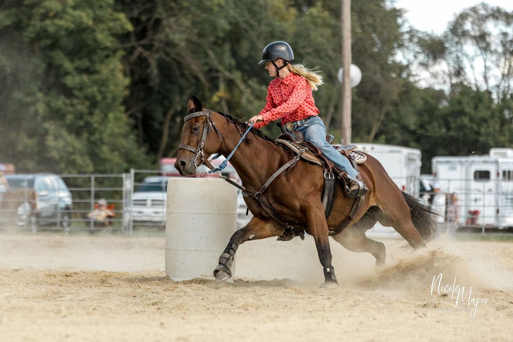 Horse and rider navigate around barrel during competitive rodeo event.