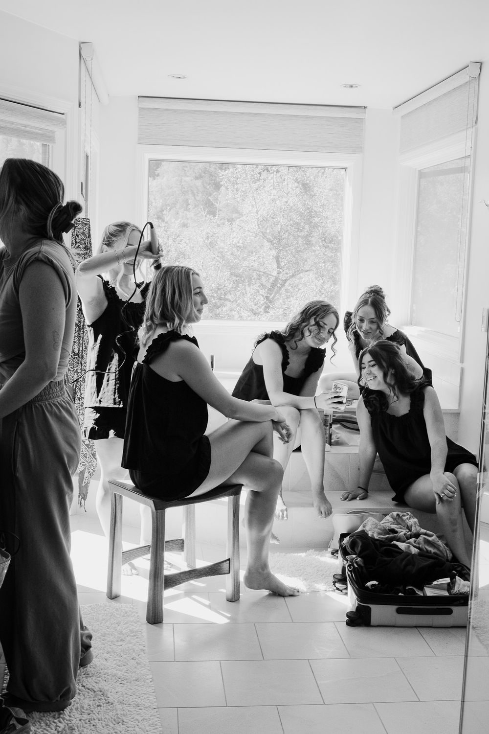 Black and white photo sequence showing dancers in leotards practicing moves on ballet barres in a bright studio.