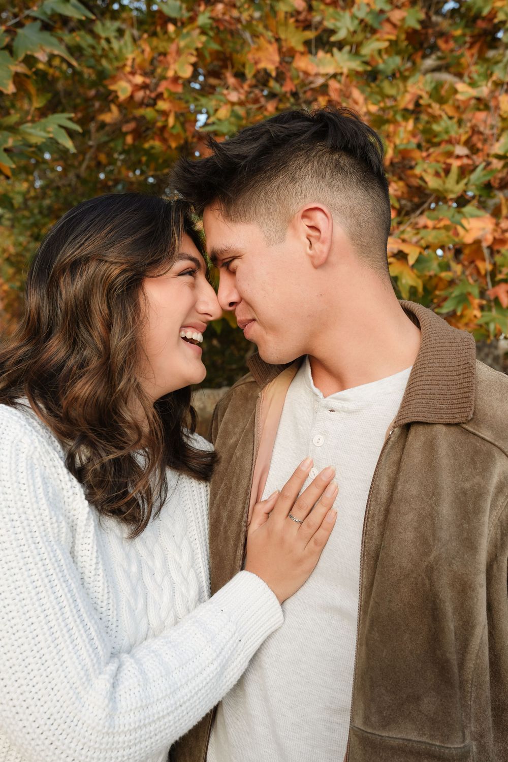 Romantic autumn portrait of a couple sharing an intimate moment in front of fall foliage.