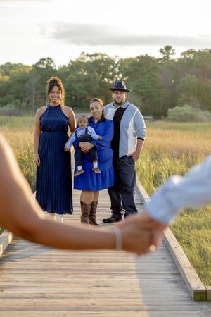 Family posing on wooden boardwalk at sunset in Matawan, NJ.