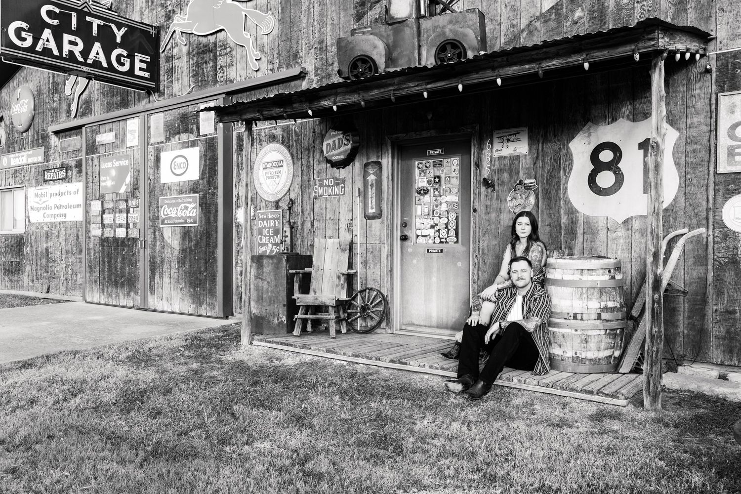 Vintage black and white photo of garage and route 81 sign with motorcycle parked outside.