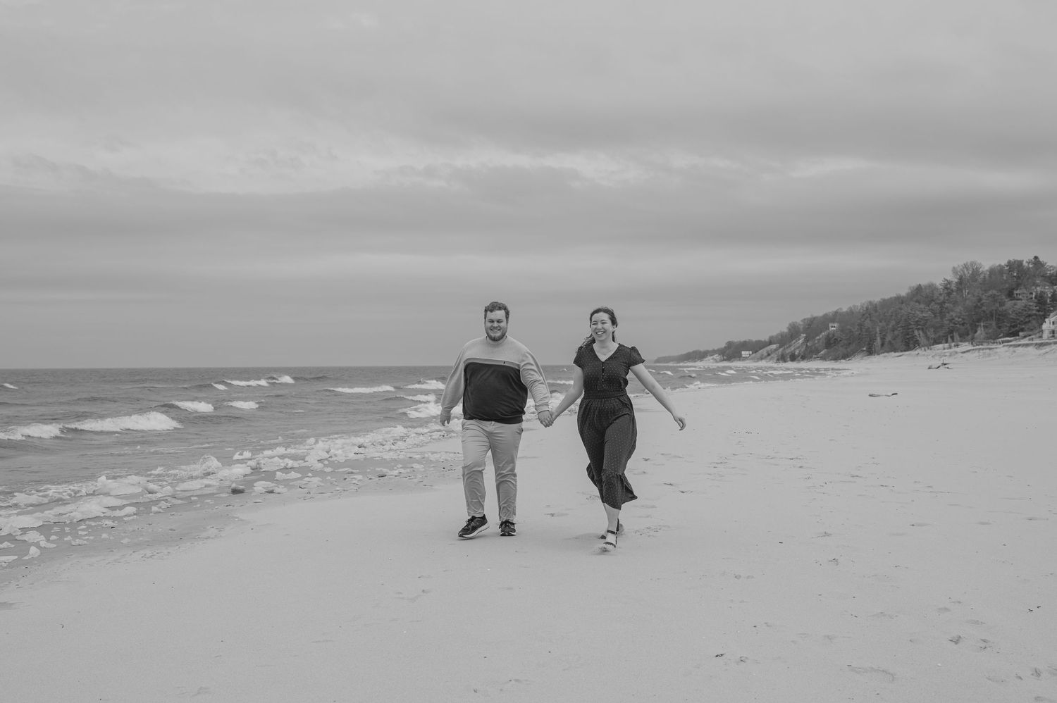 Couple racing down beach in black and white