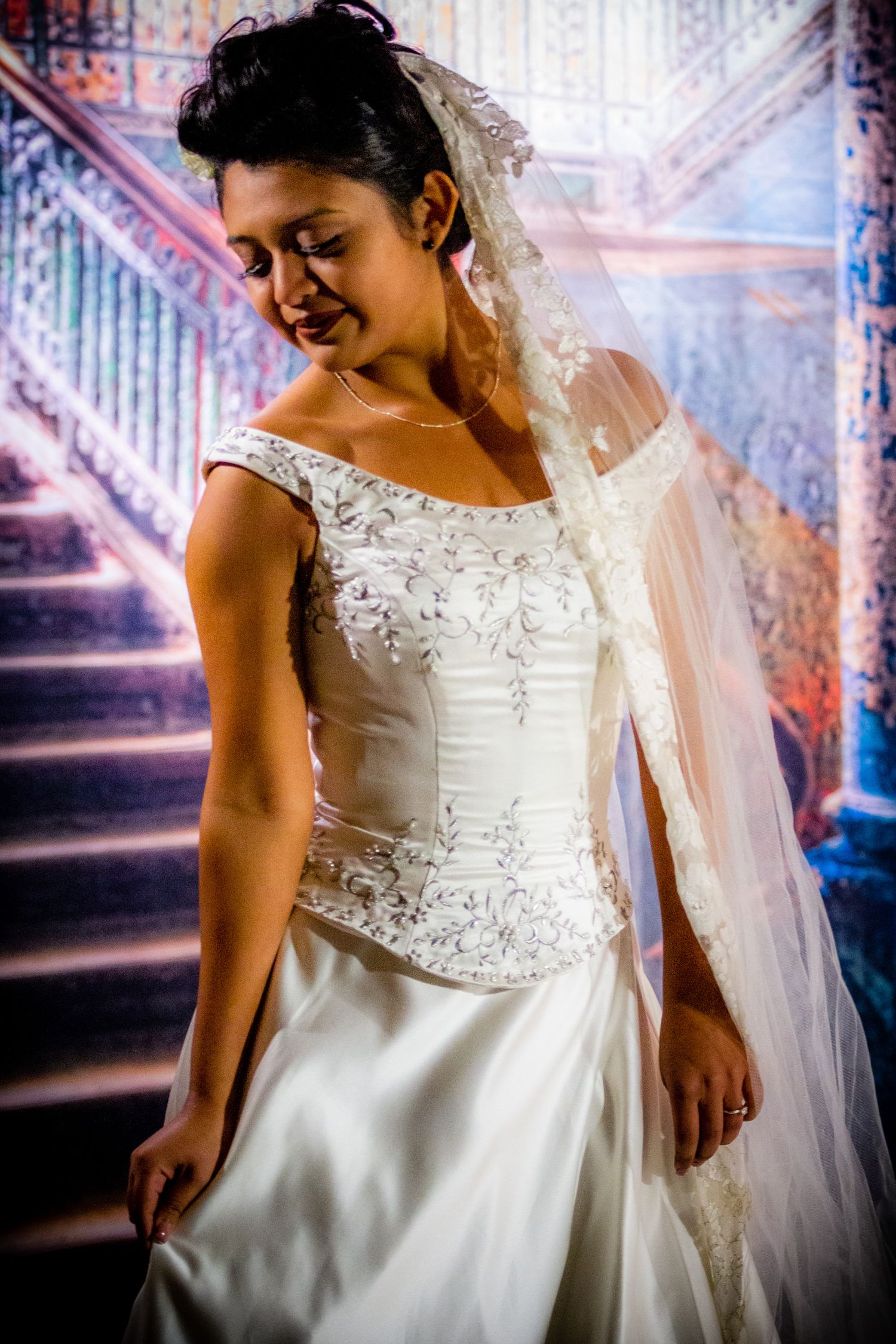 Beautiful wedding dress with beaded bodice and flowing skirt captured against colorful staircase background.