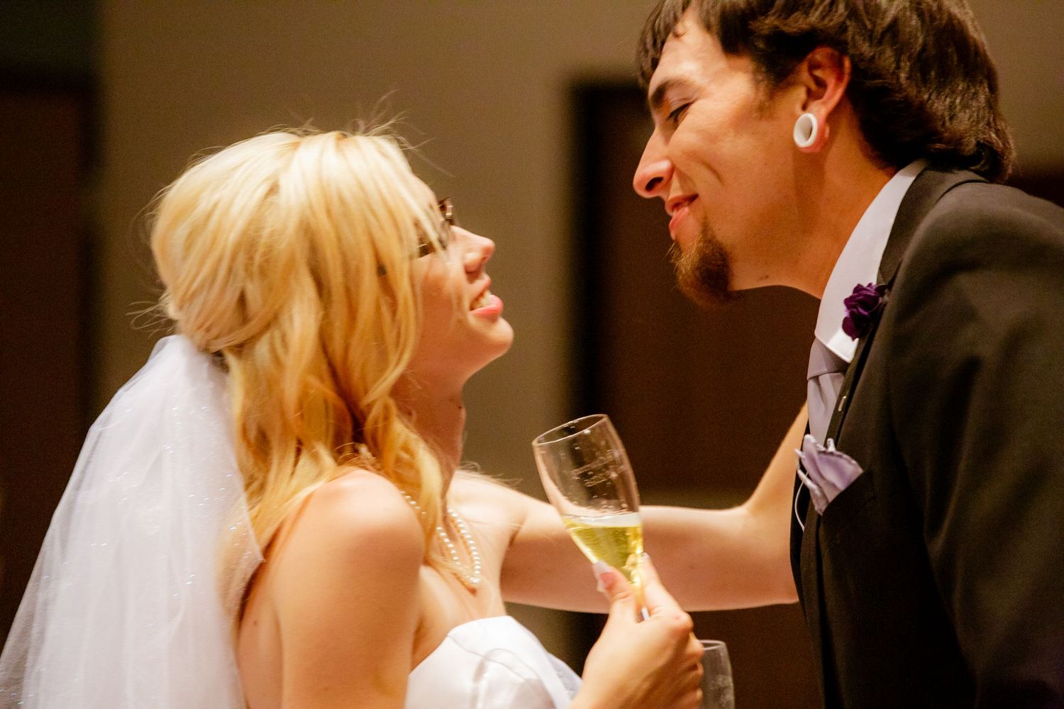 A joyful moment between newlyweds laughing and sharing champagne during their wedding celebration.