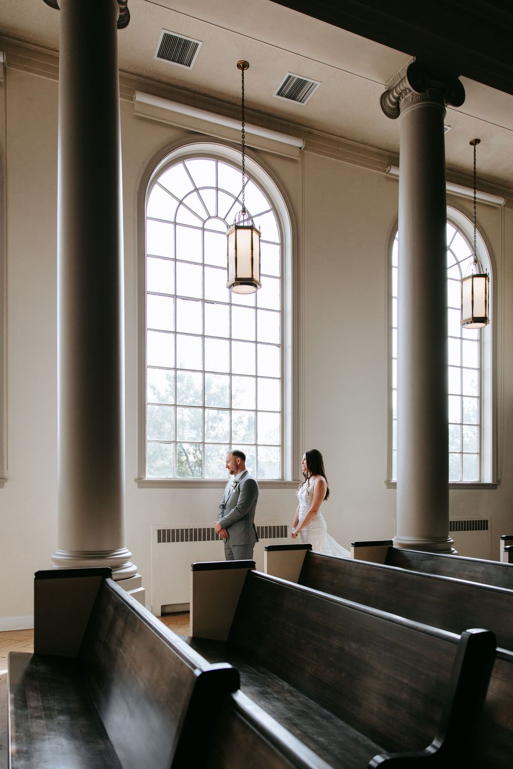 A classic church interior with tall arched windows, wooden pews, and elegant columns.