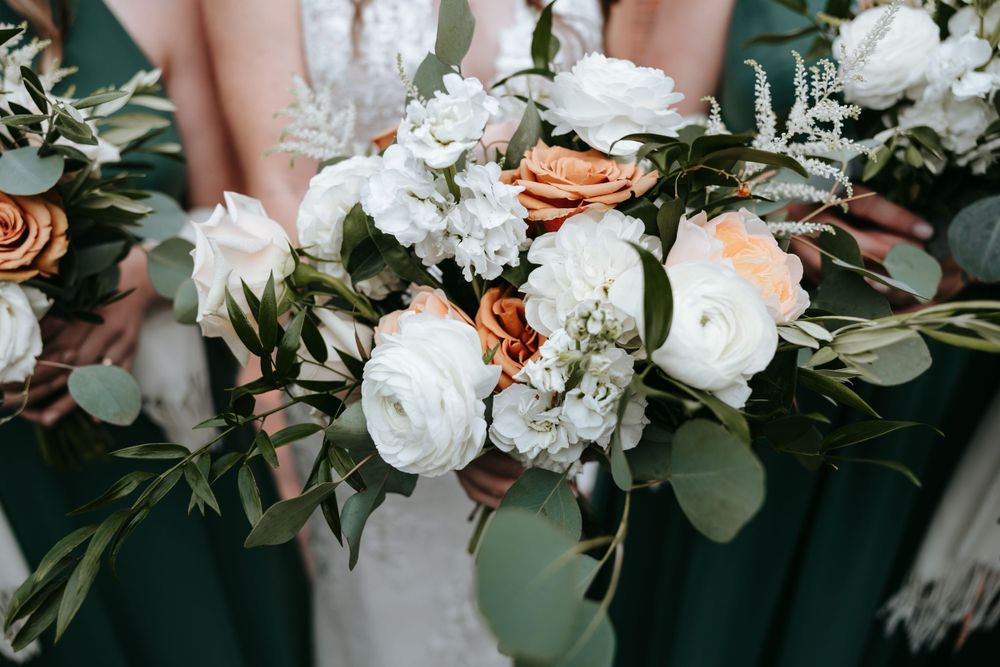 Elegant wedding bouquet with white roses, peach flowers, and eucalyptus greenery.