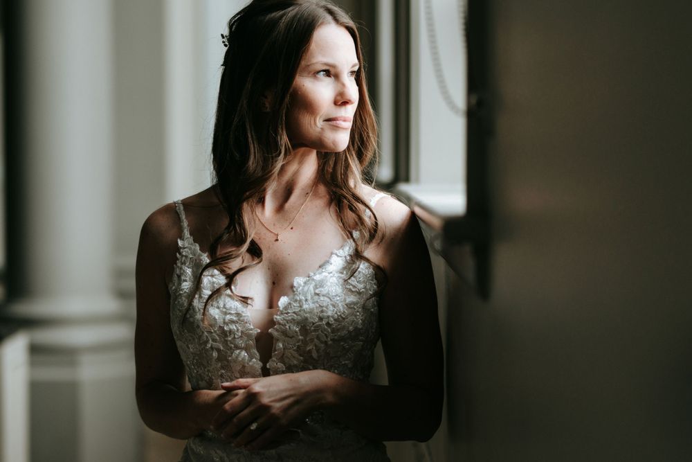 Soft window light illuminates elegant lace wedding dress details.