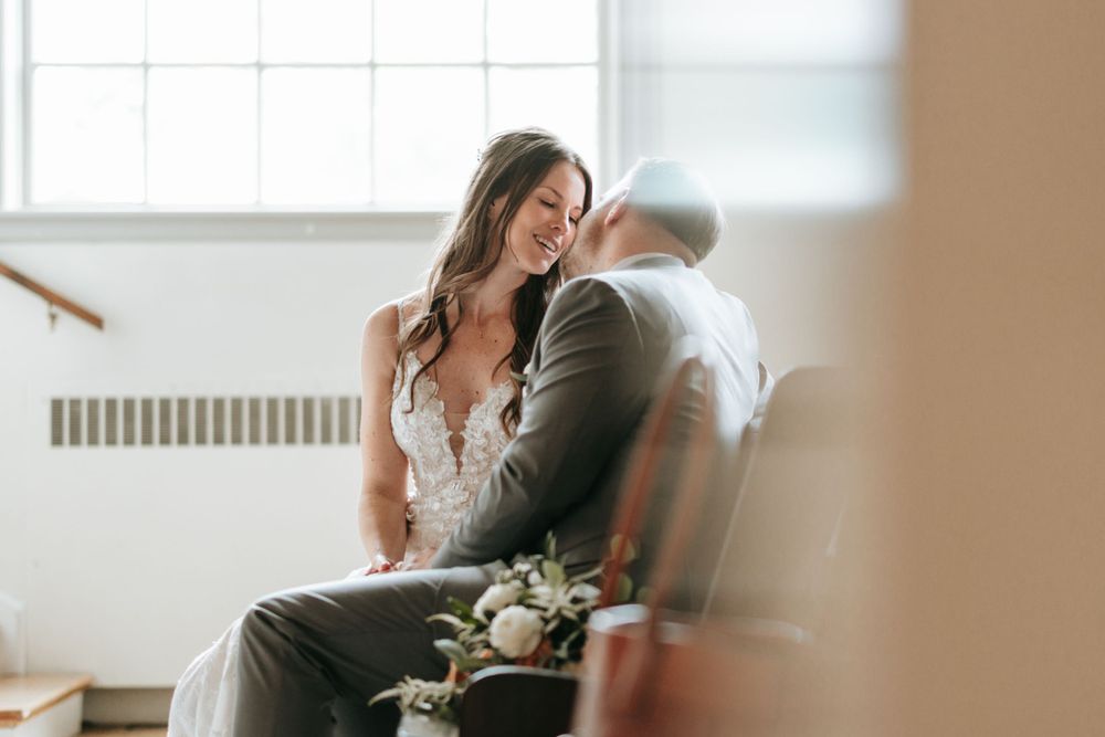 Intimate indoor wedding portrait with soft natural window lighting.